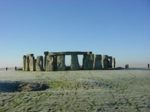 Stonehenge against a clear blue sky with the Slaughter stone in the foreground