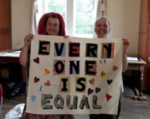 Two ladies holding a hand-made banner saying 'Everyhone is Equal'