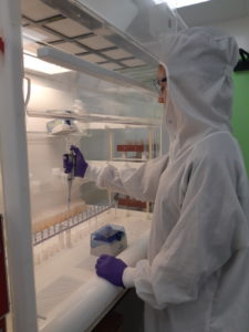 Photograph of a person in protective gear working in a lab