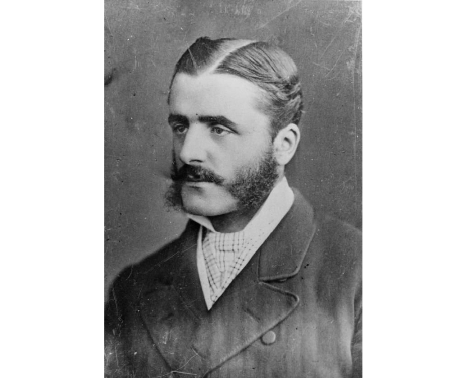 Photo of Victorian gentleman with moustache and large sideburns, wearing a stiff collar and double-breasted jacket