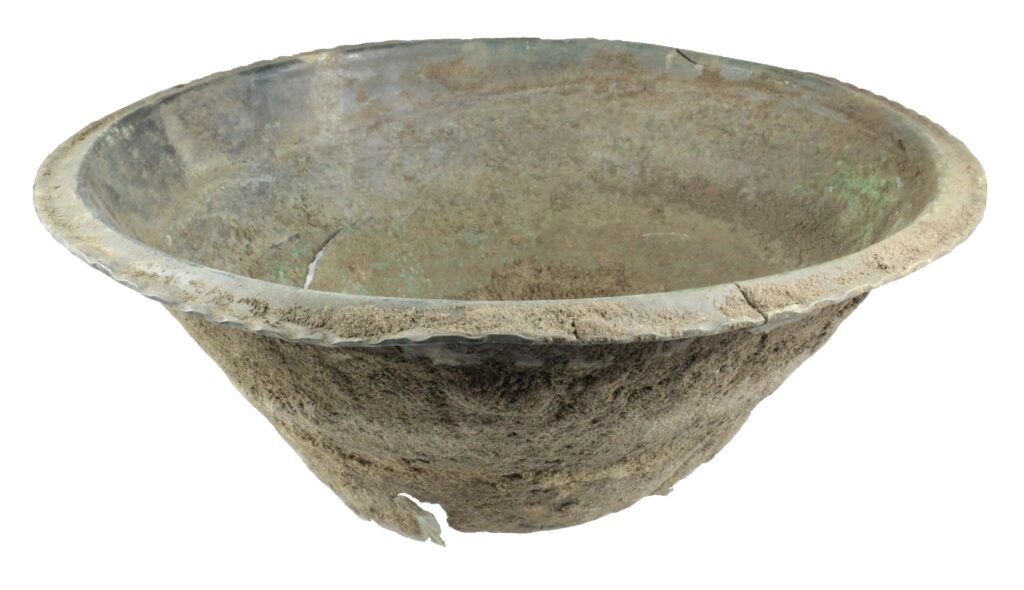 View from the side of a patinated bronze bowl, with straight sharply tapering sides.