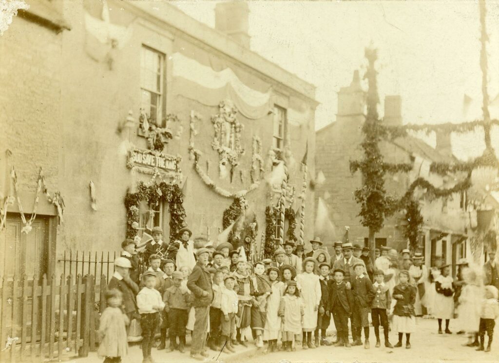 Sepia photograph of a group of well dress people in front of a decorated building
