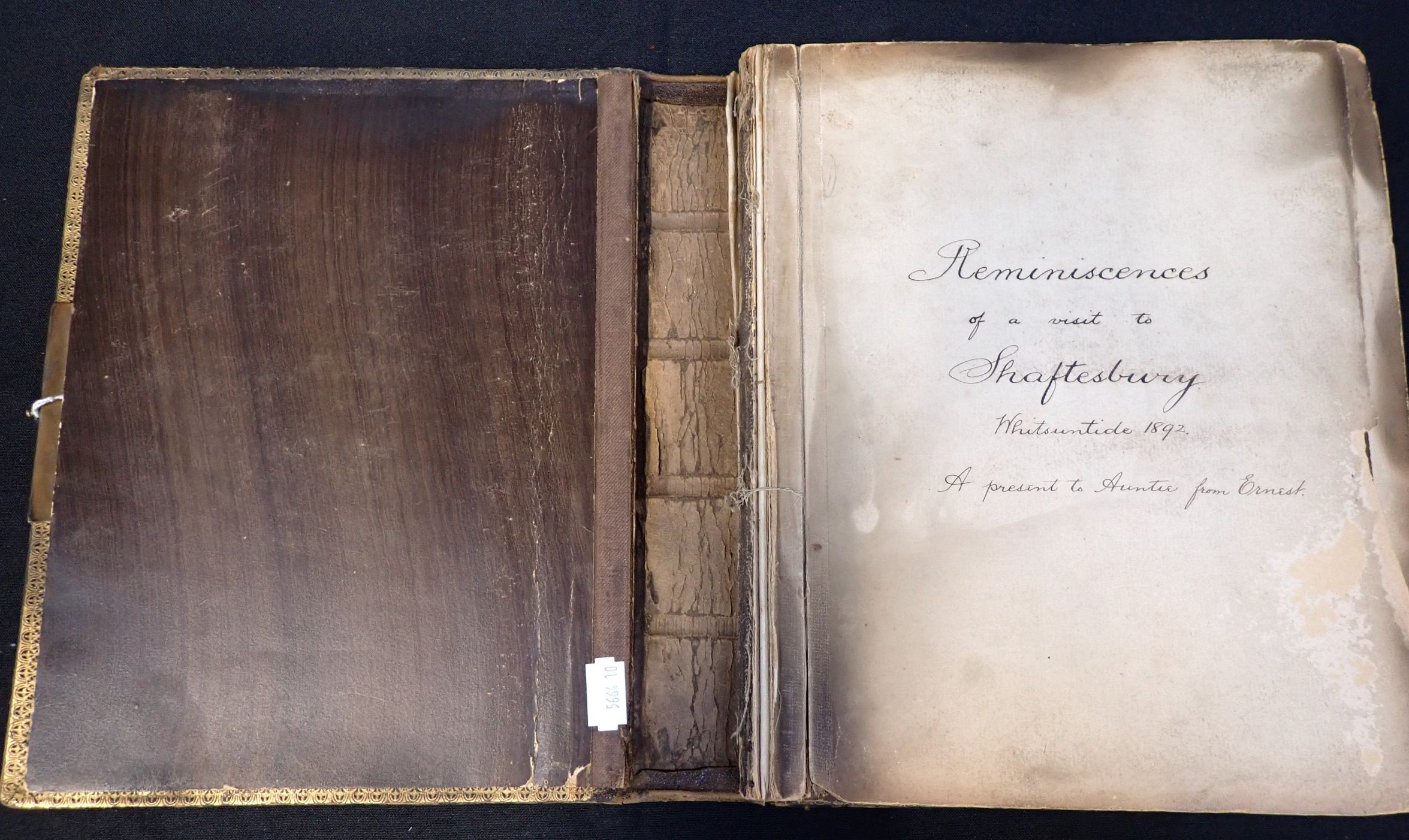 The Wiltshire Thatcher photograph album, showing the split spine and smoke damaged pages. The title page reads 'Reminiscences of a visit to Shaftesbury, Whitsuntide 1892, a present to Auntie from Ernest'.