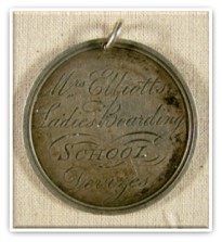 Circular silver medal inscribed with flowing handwriting