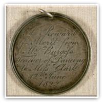 Circular silver medal inscribed with flowing handwriting.
